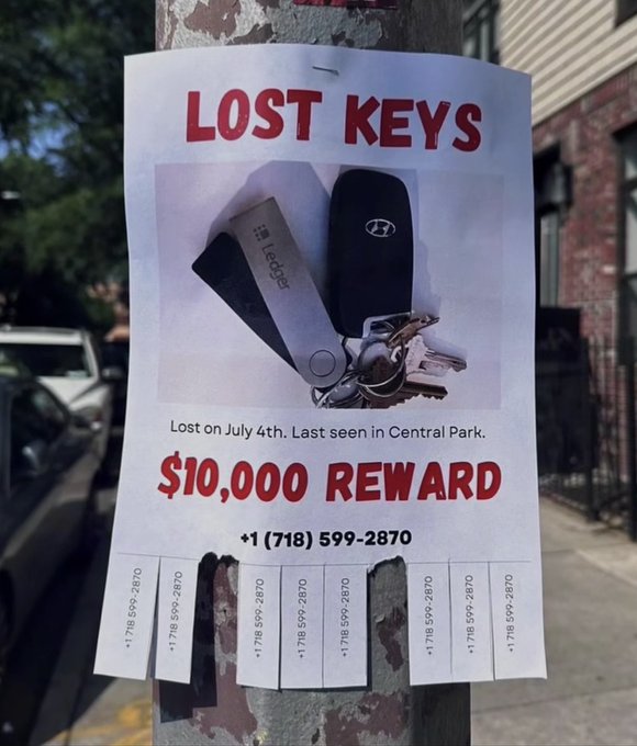 A "LOST KEYS" flyer offering a $10,000 reward, with a Ledger hardware crypto wallet pictured among the keys and contact number +1 (718) 599-2870, humorously implying the high reward is because the keys likely grant access to significant cryptocurrency holdings. The phone number is repeated on tear-off tabs at the bottom.