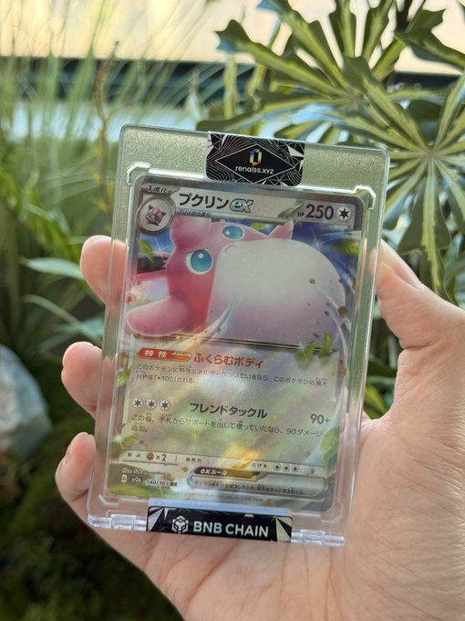 A hand holds a graded Pokémon card featuring the character Clefable (ブクリン ex), encased in a protective sleeve labeled 'BNB CHAIN' and 'renaiss.xyz'.