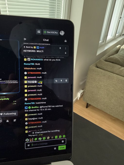 The image shows a laptop screen displaying a Twitch chat where viewers are spamming "multi" in response to a "KEYWORD: MULTI" prompt, with the streamer "Rome789" announcing they've watched a channel for 15h 35min. This visual directly illustrates the post's message about hosting a keyword giveaway on stream, where viewers are actively participating by typing the required keyword in chat to qualify.