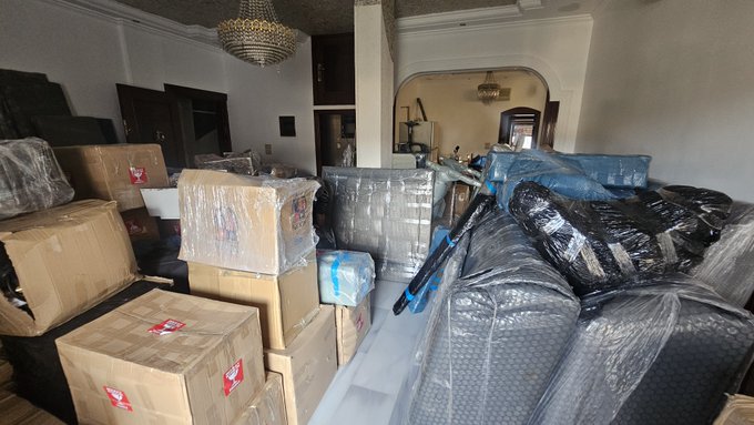 A partially packed room filled with cardboard moving boxes, wrapped furniture, and a bicycle, illustrating the 60% relocation progress described in the post. The space appears mid-transition, with belongings organized but clearly more packing and sorting still needed before the move is complete.