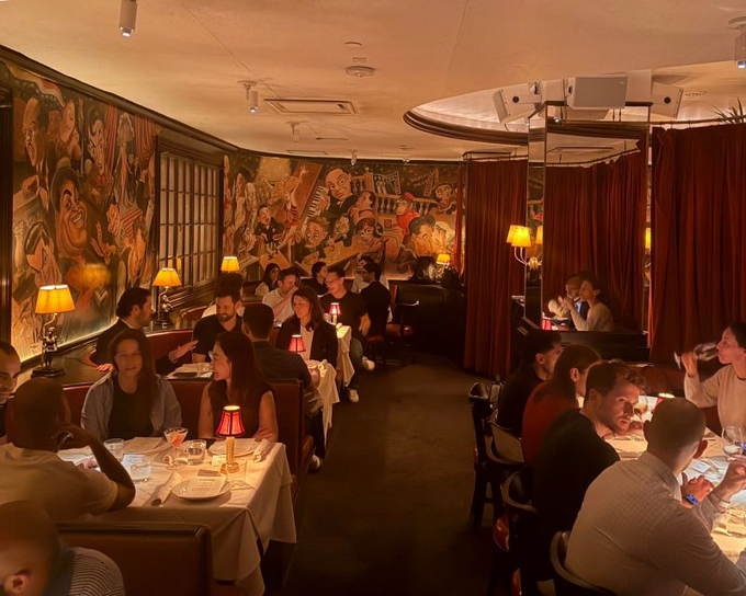 Diners enjoy an intimate dinner at a lively restaurant featuring colorful mural art and warm lighting, reflecting the social, networking-focused evening described in the post about gathering with the Turnkey crew to discuss crypto, stablecoins, and agentic commerce.