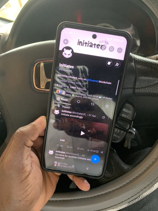 A hand holding a smartphone displaying the X/Twitter profile of 'initiates' (@initiatefi), a blockchain-related account founded in January 2024.