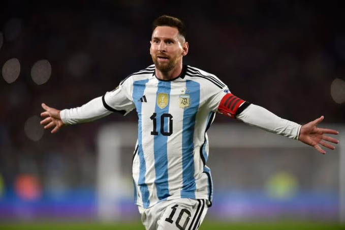 Lionel Messi wearing the Argentina #10 jersey with a captain's armband, arms outstretched in celebration on the field during a match.