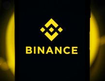 The image shows the Binance logo, featuring a yellow diamond-shaped symbol above the word "BINANCE" on a black background with glowing yellow accents. This visual corresponds to the post announcing Binance's addition of four new tokenized stocks—Securitize, StablecoinX, JPMorgan Chase, and Eli Lilly—as eligible collateral across its margin trading services.