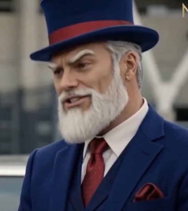 An older man with a white beard and bushy eyebrows wears a blue top hat with a red band, matching his blue suit and red tie. An 'N' logo appears in the top right corner.