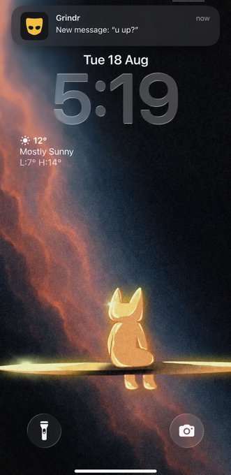 A lock screen featuring an illustration of a glowing orange fox-like figure against a cosmic sky, displayed as a phone wallpaper. A Grindr notification reads "New message: 'u up?'" above the time 5:19 and weather showing 12° Mostly Sunny on Tue 18 Aug.