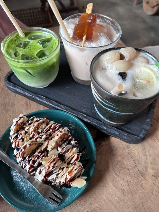 A café spread featuring a matcha latte, an iced coffee with caramel jelly, a lychee lemonade, and a crepe dessert drizzled with chocolate sauce.