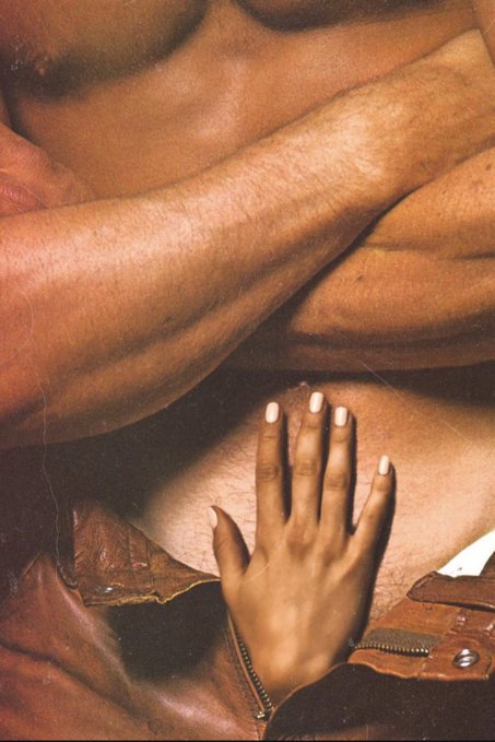 The image shows a close-up of a person's hand, with their fingers spread out as if they are about to touch or grab something. The background appears to be a grayish color, which contrasts with the brown leather jacket that covers most of the lower half of the image. There is also a small portion of another image in the bottom right corner of the photo.