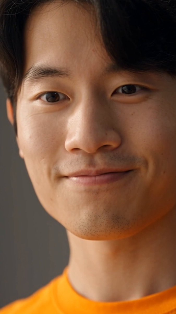 A close-up portrait of a young East Asian man with dark hair and a subtle smile, wearing an orange shirt that matches the warm tone of the caption's orange heart emoji. The image conveys a sense of quiet contentment and harmony, reflecting the "pieces falling into place" sentiment through his calm, satisfied expression.