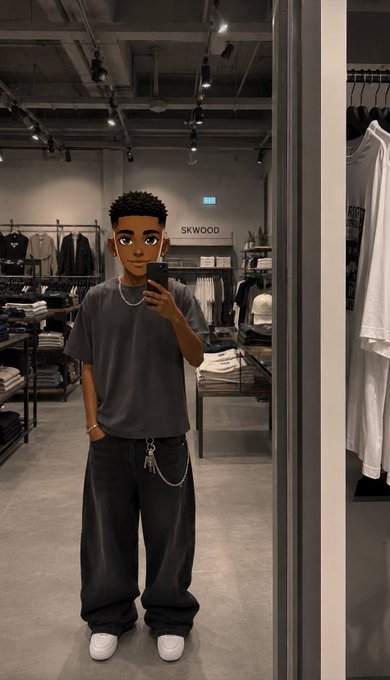 A mirror selfie of a young man in a dark oversized T-shirt and baggy jeans, with a chain accessory, inside a clothing store labeled 'SKWOOZ'.