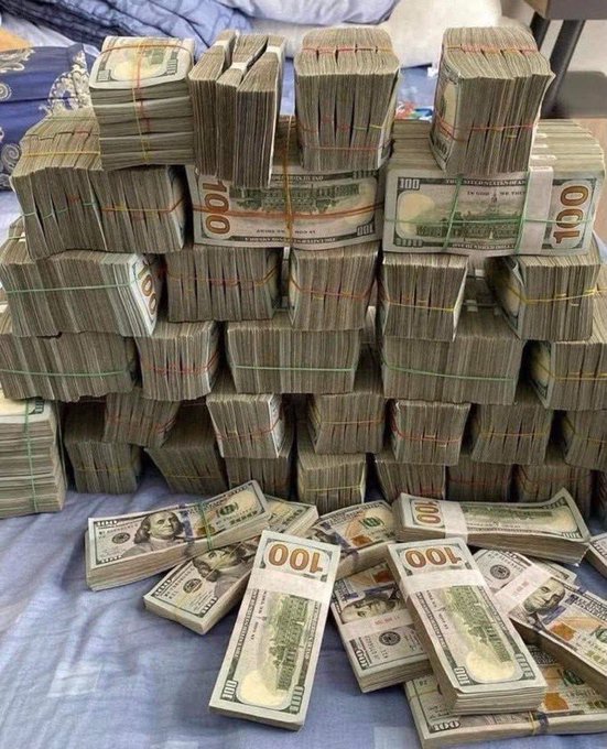 Large stacks of bundled $100 US dollar bills piled on a bed.