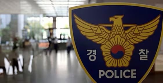The image shows a close-up of a South Korean police emblem—a golden eagle with spread wings above a taegeuk symbol on a shield-shaped blue badge, with the Korean characters "경찰" (Police) and the English word "POLICE." The blurred background appears to be a public building or station interior, lending an ominous, foreboding atmosphere that complements the post's expression of fear or concern.