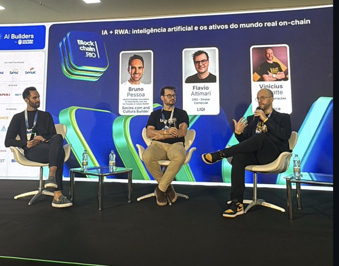 A panel discussion at the 'BlockchainRIO' event about 'IA + RWA: inteligência artificial e os ativos do mundo real on-chain,' featuring speakers Bruno Pessoa, Flavio Altimari, and Vinicius.