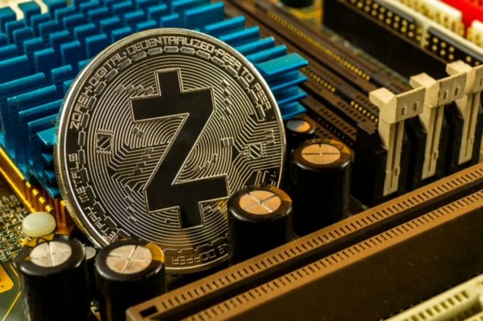 A close-up photograph of a Zcash (ZEC) cryptocurrency coin resting on the components of a computer motherboard.