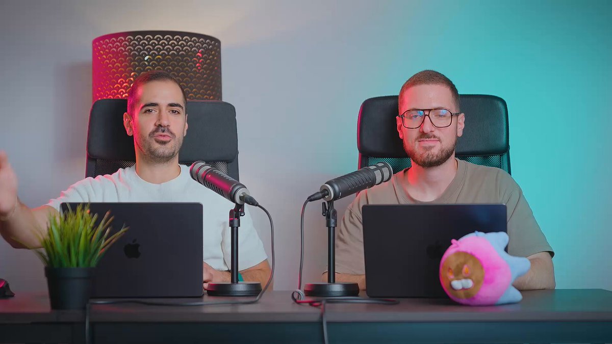 The image shows two men sitting at a table with microphones, each using their own laptop computer. They appear to be engaged in an interview or discussion about cryptocurrency. The background features a lamp that illuminates the scene, creating a professional atmosphere for the podcast recording.