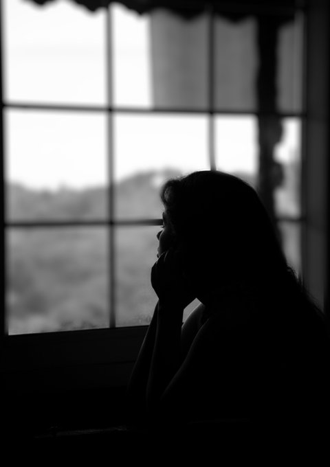 A black-and-white silhouette captures a contemplative figure in profile, resting their chin on their hand while gazing out a multi-paned window toward a softly blurred horizon, evoking the introspective mood of weaving hope and looking toward an unwritten future. The image visually echoes the post's metaphor of the mind as a loom, the window as a portal to possibility, and the singular, quiet moment of creative vision.