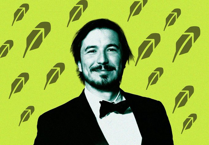 A stylized photo of Keanu Reeves wearing a bow tie against a bright green background patterned with feather/quill logos, referencing his role as John Wick.