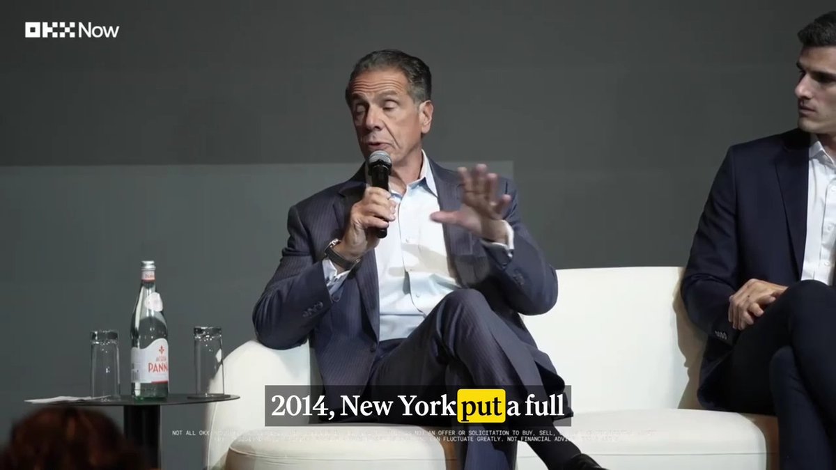 Andrew Cuomo speaks into a microphone at the OKX Now event, with a caption reading "2014, New York put a full" visible on screen, as he discusses the failure of the CLARITY Act.