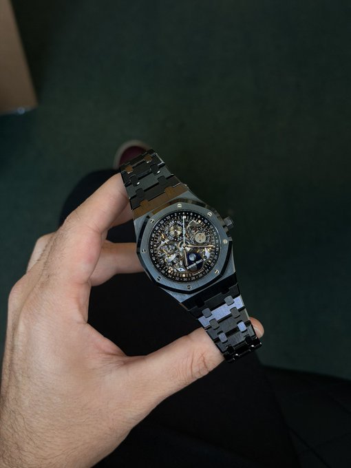 A hand holds up an Audemars Piguet Royal Oak Perpetual Calendar Openworked watch with a black ceramic case and bracelet, its open dial revealing the intricate movement—fitting the post's reference to luxury timepieces as a "gift for the bulls."