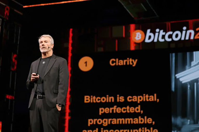 A man in a black suit stands on a stage presenting at a Bitcoin 2022 conference, with a slide titled '1 Clarity' and text reading 'Bitcoin is capital, perfected, programmable, and incorruptible.'