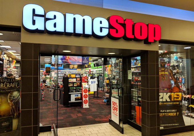 The image shows a GameStop store with its doors open for business. A sign above the entrance displays "GameStop", indicating that this is an establishment associated with the gaming company. The store appears to be located within a mall, as there are other stores visible in the background. The focus of the post is on the stock market and how it has been affected by GameStop's success.