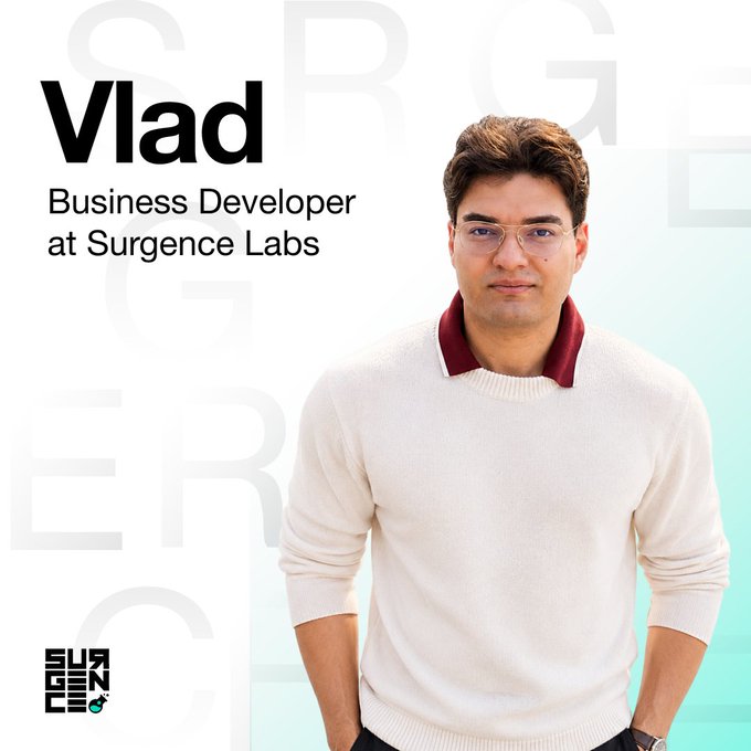 A professional profile card for 'Vlad', a 'Business Developer at Surgence Labs', showing him smiling and wearing glasses and a cream sweater over a maroon shirt.