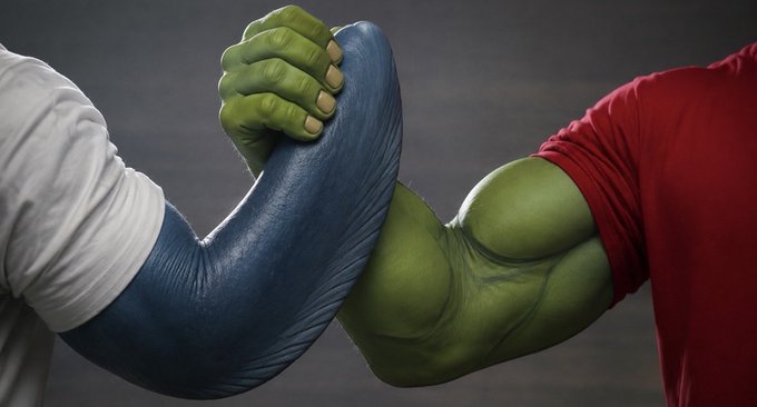 A stylized image of an arm wrestling match between two muscular, cartoon-like characters with green hands and blue skin, set against a dark background.