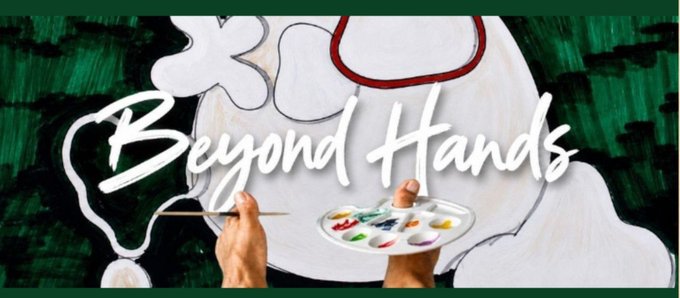 A mural with the stylized white text 'Beyond Hands' is being painted on a green wall, showing hands holding a paintbrush and a colorful paint palette.