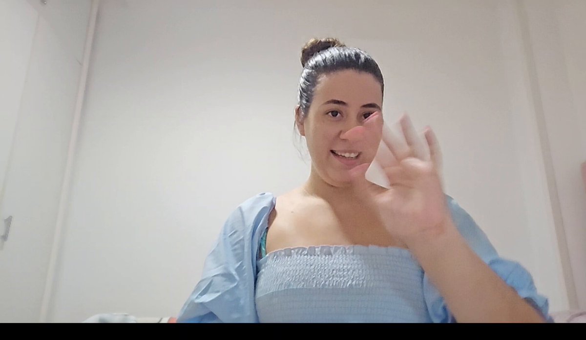 The image features a woman wearing a blue dress with her hand raised in front of her face as if she's waving or making a gesture. The background appears to be a white wall, which contrasts nicely with the woman's outfit. The caption provided seems unrelated to the main subject and does not provide any additional information about the content of the image.