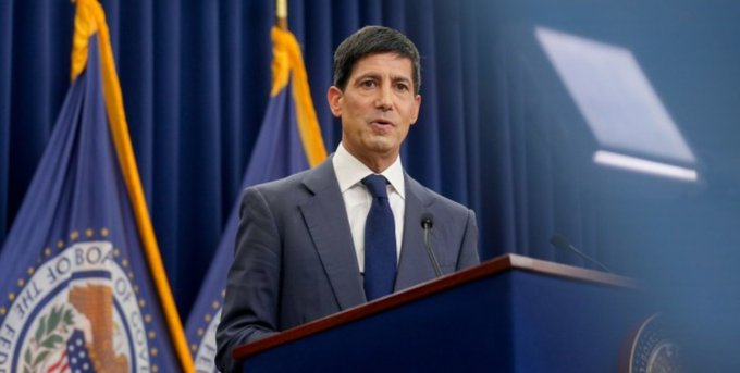 A man in a dark suit stands at a podium speaking at what appears to be a Federal Reserve press briefing, with a partial "Department of the Treasury" seal visible on a blue flag behind him. The image illustrates the Federal Reserve announcement of injecting $8.632 billion in liquidity into the U.S. economy, suggesting an official statement on monetary policy.