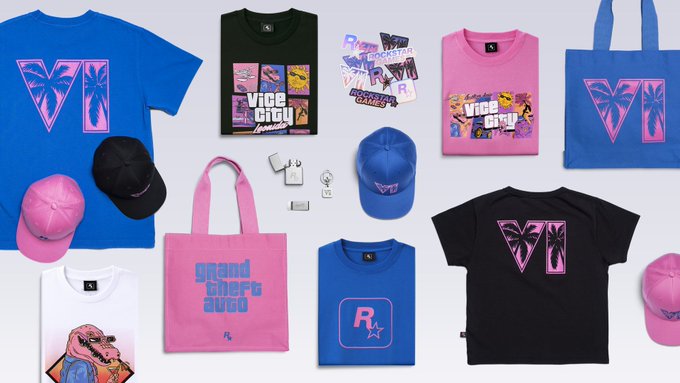 A flat-lay display of Vice City branded merchandise including pink and blue t-shirts, caps, tote bags, and accessories featuring 'Grand Theft Auto' and 'Rockstar' logos.