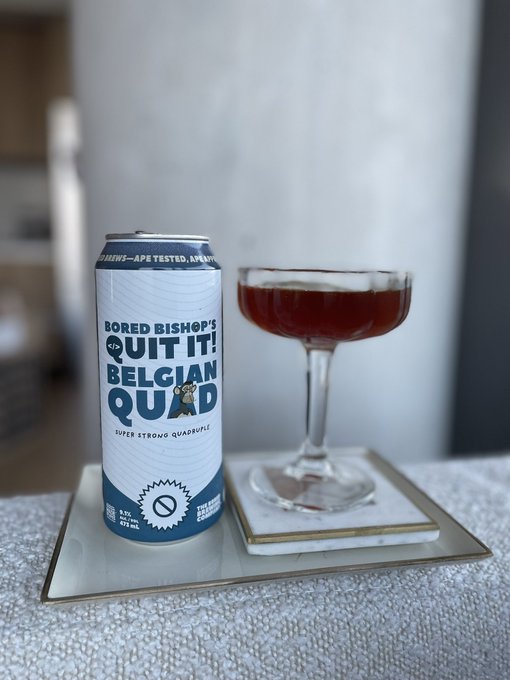 A tall can of 'Bored Bishop's Quit It! Belgian Quad' (Super Strong Quadruple, 9.5% ABV, 475 mL) sits next to a coupe glass filled with dark beer.