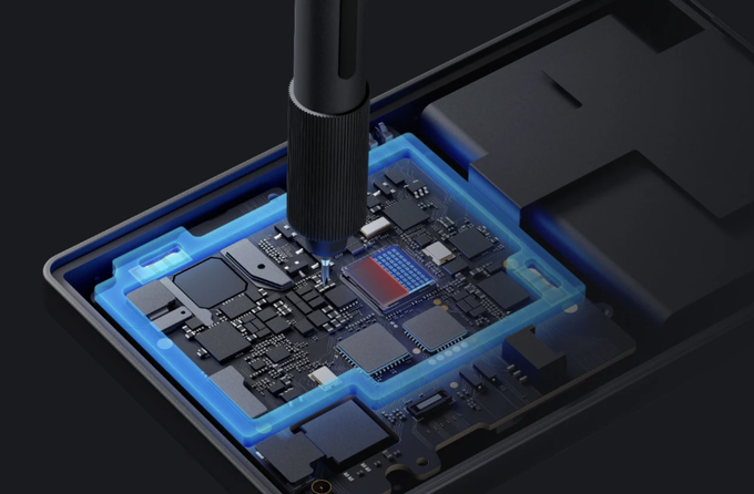 A close-up view of electronic components on a circuit board being inspected or repaired with a precision screwdriver, featuring blue glowing outlines around certain components.