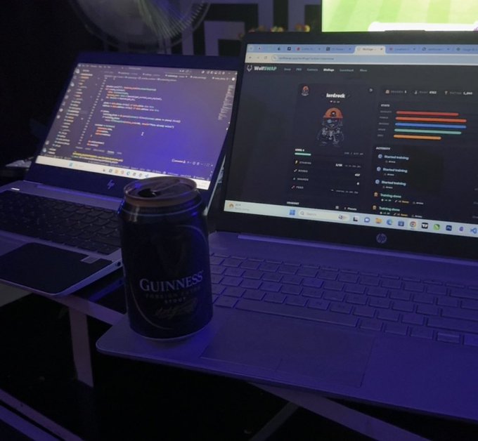 The image features a desk with two laptops open side by side, along with a can of Guinness beer placed between them. The scene suggests that someone might be working or studying while enjoying their drink.
