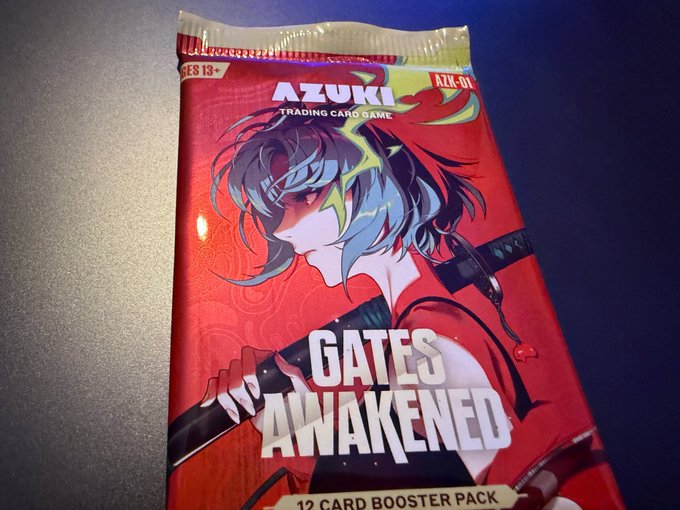 A sealed "Gates Awakened" 12-card booster pack from the Azuki Trading Card Game (AZK-01, ages 13+) featuring an anime-style character with teal hair, ready to be ripped open. The pack's vibrant red packaging and booster pack format perfectly capture the anticipation of opening a presale pack.