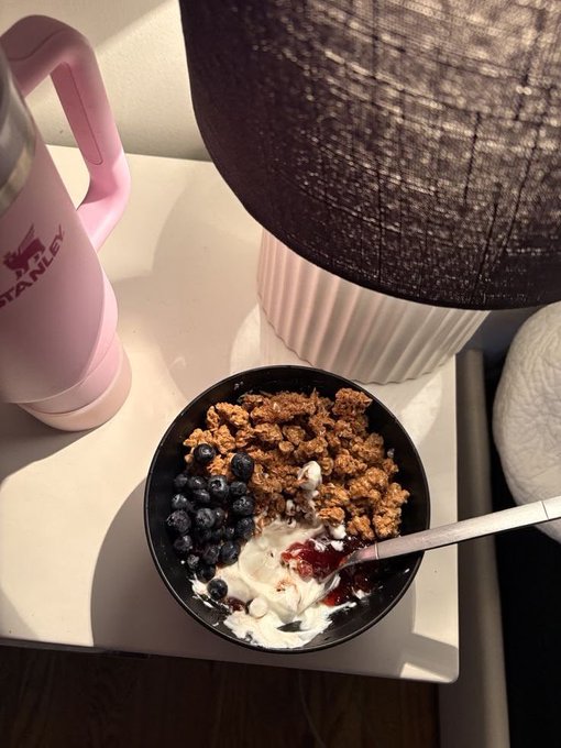 The image features a black bowl filled with cereal, topped with blueberries and yogurt, placed on a white table next to a pink thermos. The thermos has the word "quip" written on it, which suggests that this meal could be part of a rewards program or a promotional offer for Quip Network.