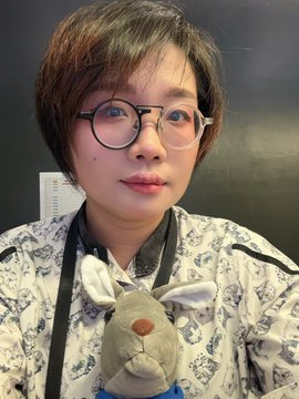 The image features a woman wearing glasses, a shirt with a cartoon rabbit design, and holding a stuffed animal. The background of the photo is black, which contrasts with the white text that reads "GM Look at you like.... Haning+_True Face 0.1 eth on @sealed_art". This post seems to be promoting an item or brand related to the woman's appearance in the image.