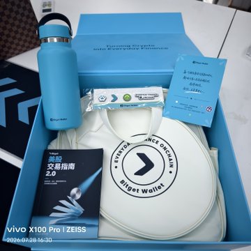 A blue Bluetooth speaker and a white drawstring bag with "Bitget Wallet" branding inside a gift box, with a watermark reading vivo X100 Pro | ZEISS.