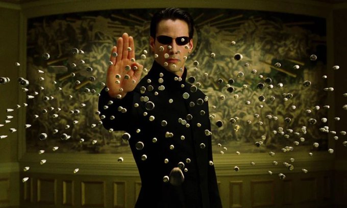 A man in sunglasses freezes a swarm of bullets mid-air with his raised hand, symbolizing control over an unstoppable force—mirroring the post's message that Bitcoin's rise is inevitable and those who ignored the early signs will feign ignorance.