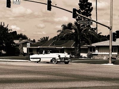 A vintage car drives along a suburban street beneath a "Providence" street sign and a US Route 66 shield, capturing a nostalgic mid-century Americana scene that complements the classic "Passing Through" artwork on objkt.com.