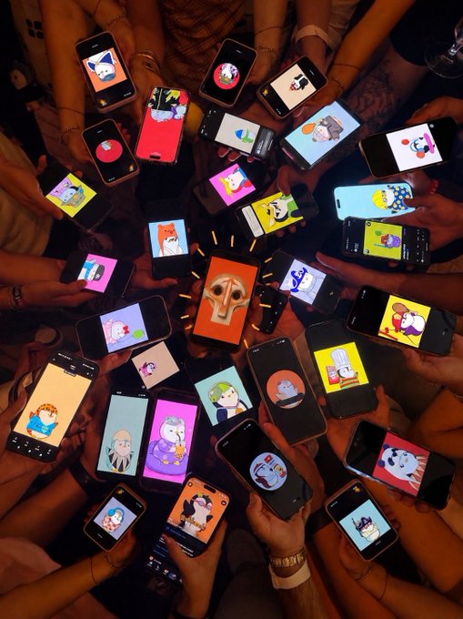 A group of hands holding smartphones in a circle, all displaying different cartoon or character images, with a central phone featuring a dog illustration surrounded by drawn-on sparkles.