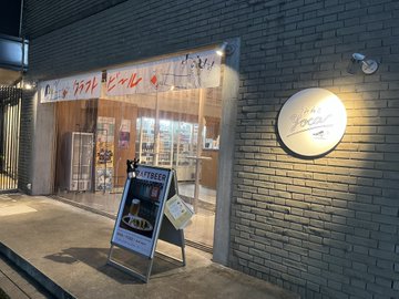 The exterior of a Japanese restaurant at night with illuminated signage and a chalkboard sign on the sidewalk.