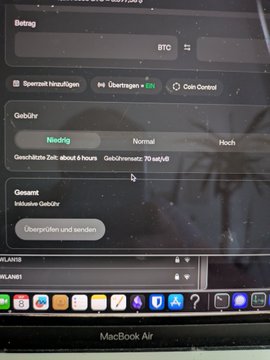A MacBook Air screen displays a German-language cryptocurrency withdrawal interface showing BTC balance, network fee selection (Niedrig/Normal/Hoch), and a transaction time estimate of "about 4 hours."