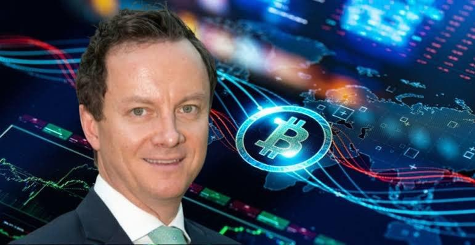 A man in a dark suit and green tie is superimposed against a stylized digital background featuring financial charts, a glowing Bitcoin logo, and a world map.