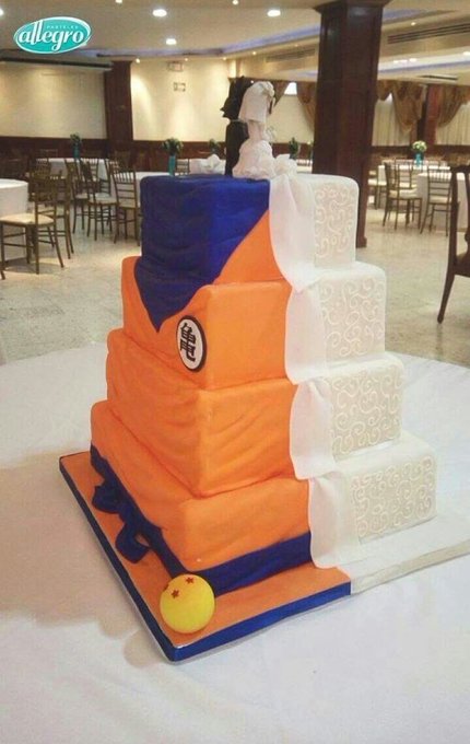 The image features a three-tiered cake with orange, white, and blue layers, resembling a dragon's body. The cake is displayed on a table covered with a white cloth. In front of the cake, there is a yellow ball, possibly representing a trophy or decoration for an event. The background shows several dining tables arranged in rows, suggesting that this might be a wedding reception or a similar gathering where guests can enjoy food and drinks together.