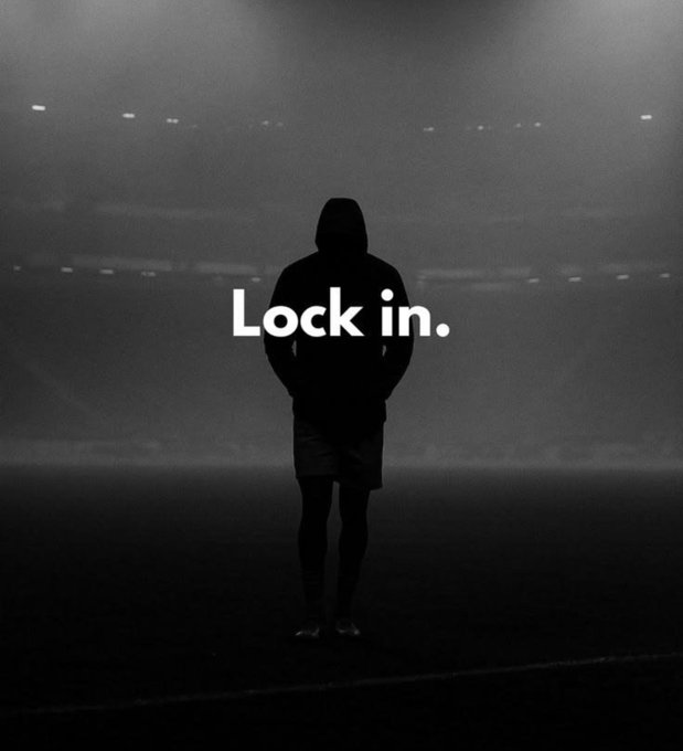 A black and white silhouette image of a hooded figure standing in a stadium with the bold text 'Lock in.' overlaid in the center.