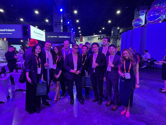 A group of attendees pose together at the Sibos conference, with visible signage for "SwissFintech," "accessfintech," and "CLEARWIRE" in the background, as they appear to represent Quant ($QNT) networking and promoting the Overledger platform at the financial industry event.