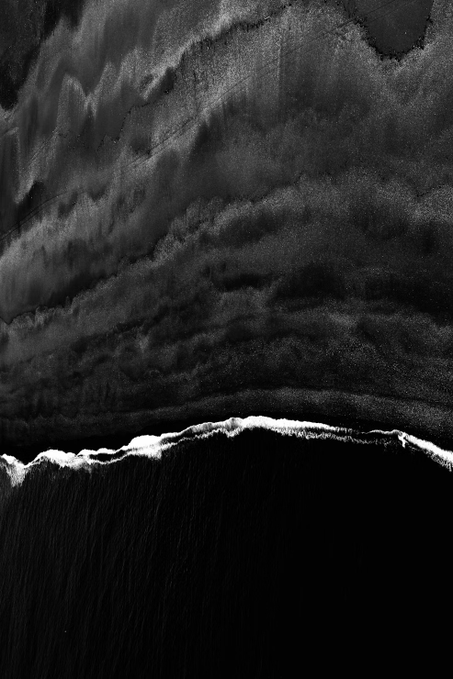 The image is an abstract black and white photograph featuring swirling, cloud-like dark patterns in the upper portion, separated from a dark lower area by a jagged line of white foam or froth resembling a shoreline. 

The abstract nature of the image, with its moody, high-contrast black and white tones, evokes a sense of uncertainty and turbulence that mirrors the post's message about patiently waiting for the market to trigger while short positions remain open.