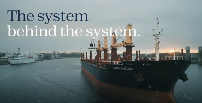 A video thumbnail or banner showing a large cargo ship labeled 'ETHRA MARITIME' docked in a port at sunset, overlaid with the white text 'The system behind the system.'