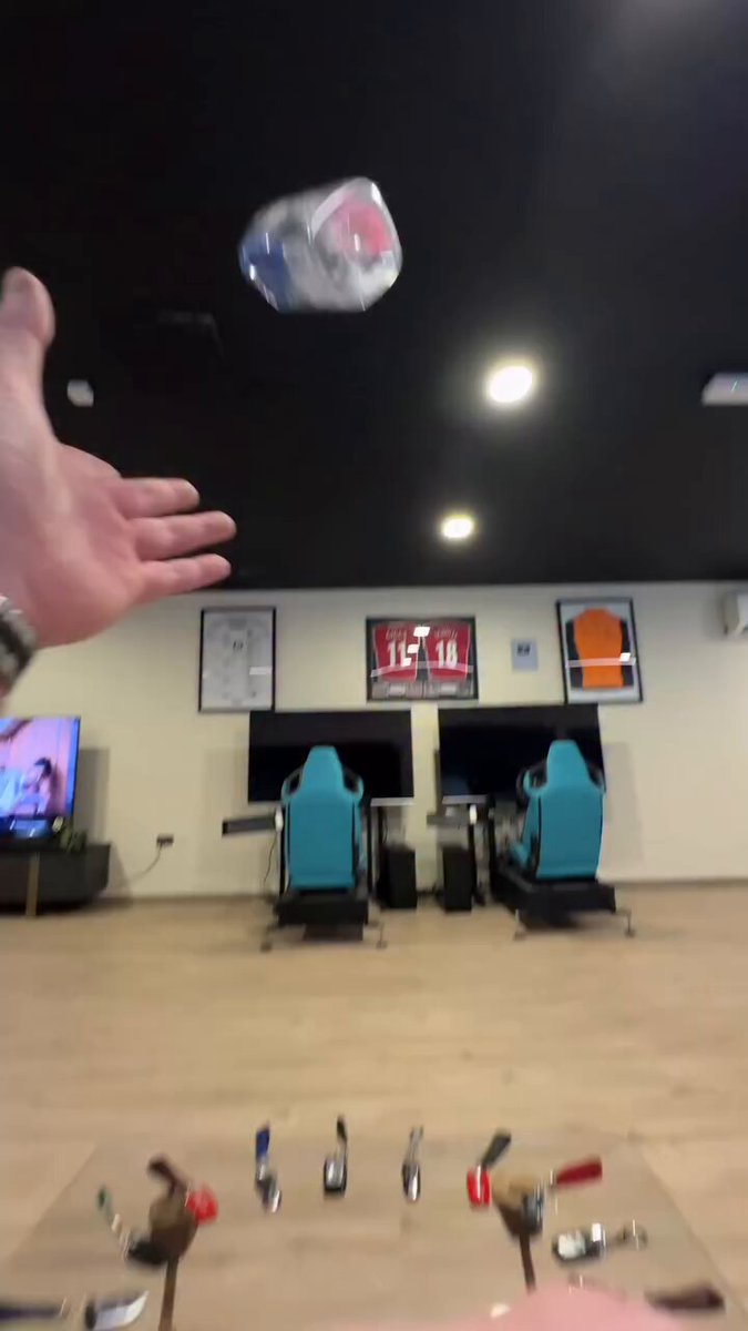 The image shows a person's hand holding a plastic bag, which appears to be a soda can or a piece of trash. There are two chairs visible in the room, one near the center and another towards the right side. The scene takes place in an indoor setting with a TV mounted on the wall above the left chair. A clock is also present in the room, located close to the center of the image. The post includes text that reads "Us in few years Believe it." This message seems to be related to the person holding the plastic bag or trash item, possibly indicating an environmental concern or a call for action regarding waste management and recycling practices.